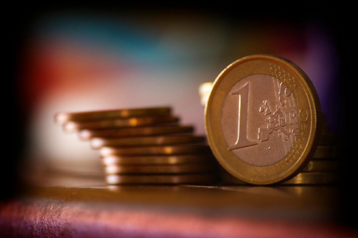 Minca 1 euro pred stohom eurocentových mincí na farebnom pozadí.