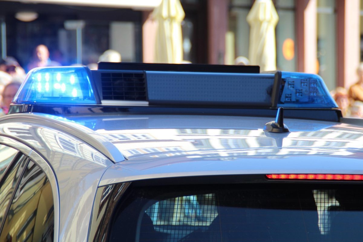 Policejné vozidlo so zapnutými modrými majákmi na ulici v meste.