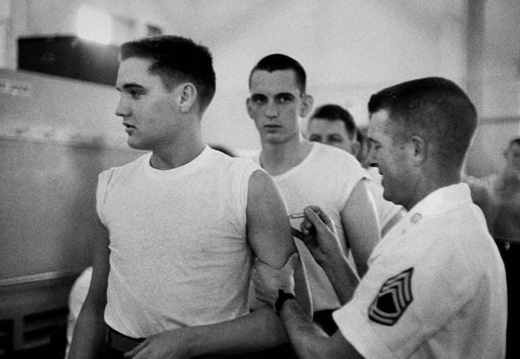 Muž dostáva vakcínu počas vojenskej prehliadky, niekoľko vojakov čaká v rade, USA, 20. storočie.