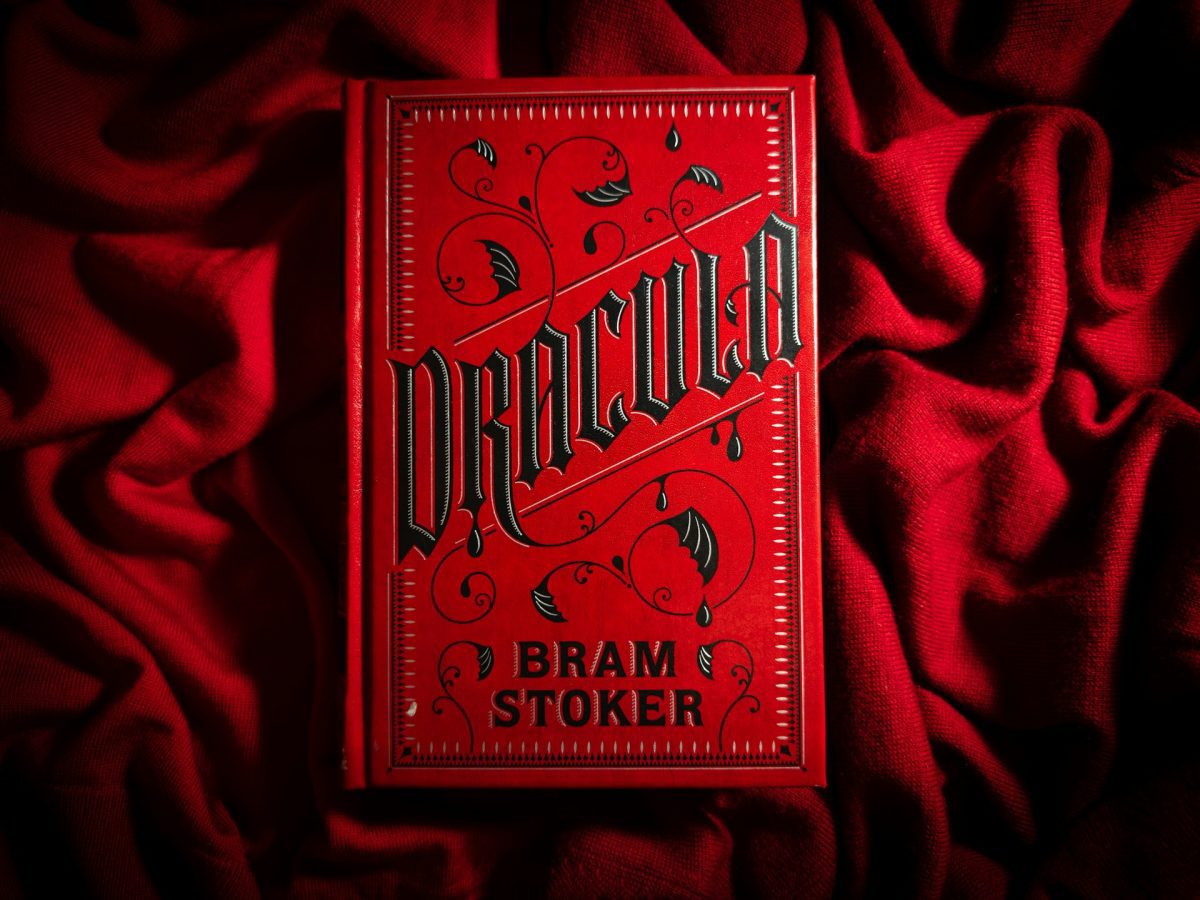 Kniha Dracula s červeným obalom položená na látke, gotický dizajn písma zvýrazňuje hororovú tematiku.