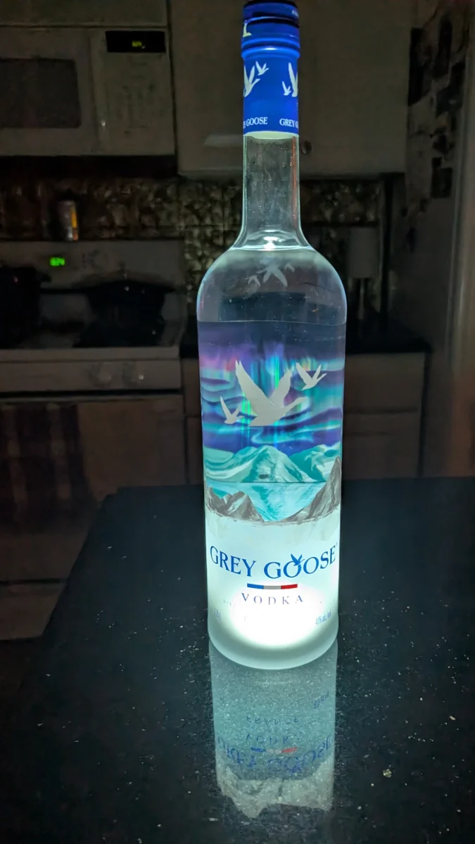 Fľaša vodky na tmavom pozadí so zaujímavým dizajnom v popredí.