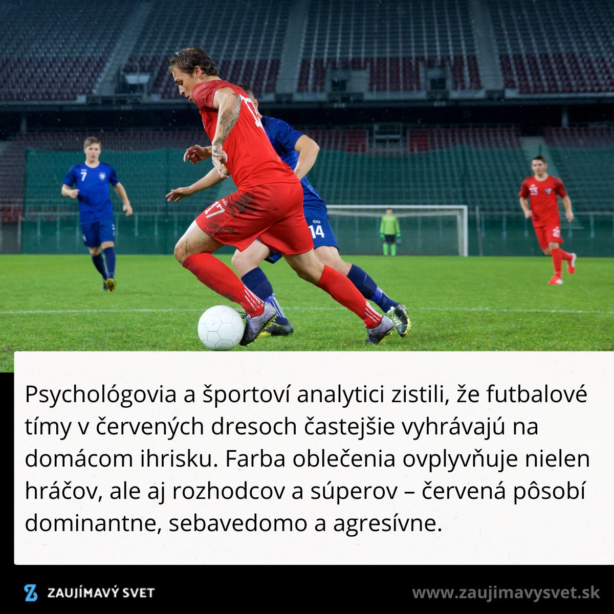 Futbalista v červených dresoch pri hre na štadióne, súper v modrom sa snaží získať loptu.
