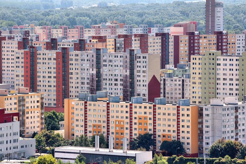 Paneláky v radovej zástavbe, farebné bytovky na sídlisku obklopené zeleňou.