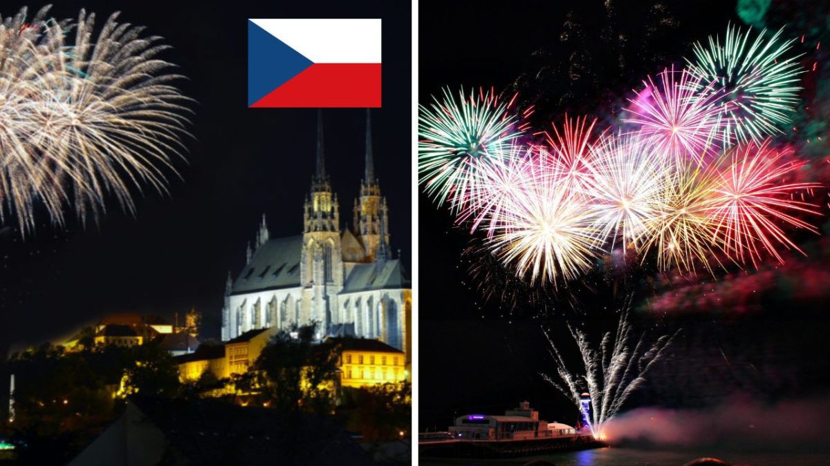Ohňostroj nad historickou budovou s českou vlajkou v pozadí, oslava noci plná svetla a farieb.