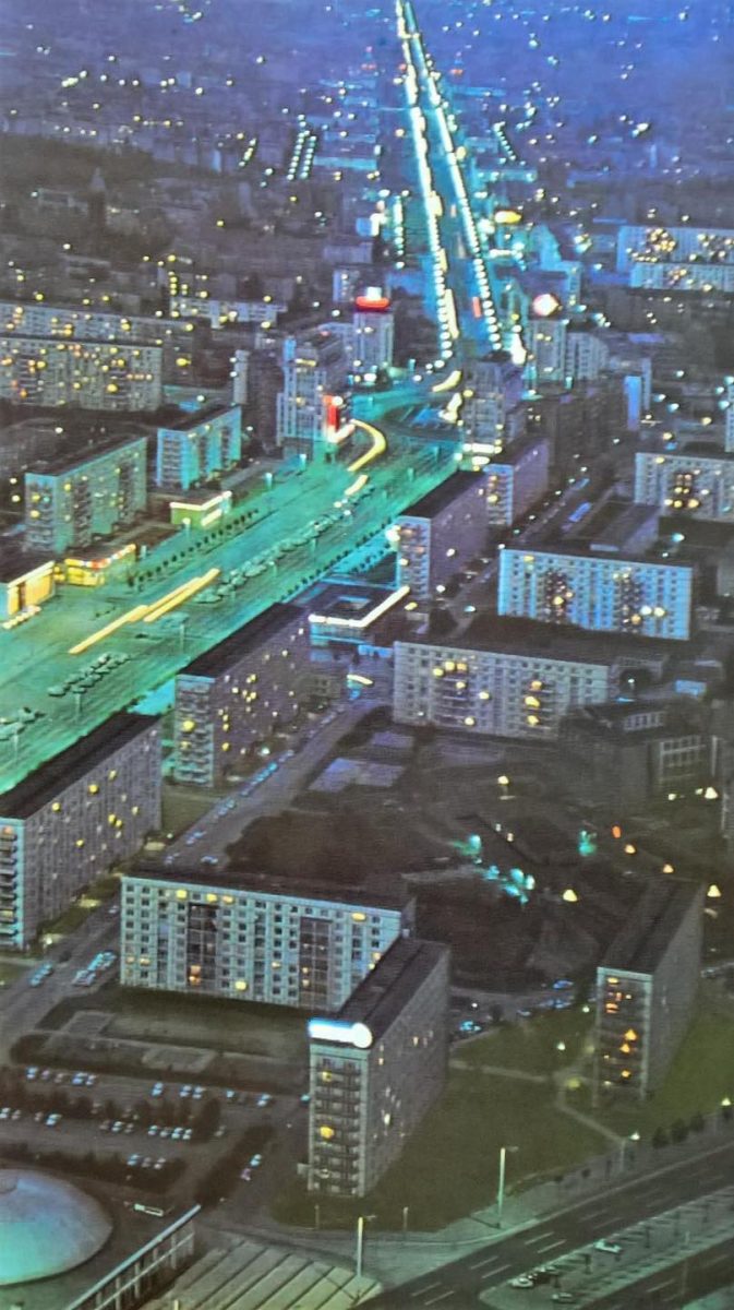 Nočná letecká snímka osvetlenej ulice s panelákmi v modernom meste.