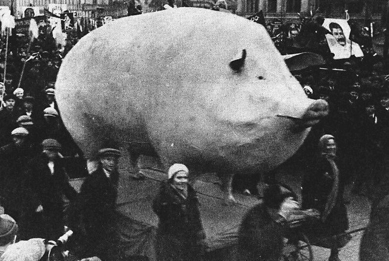 Masívne prasa na podstavci je súčasťou sprievodu plného ľudí na historickom podujatí v čiernobielom prevedení.