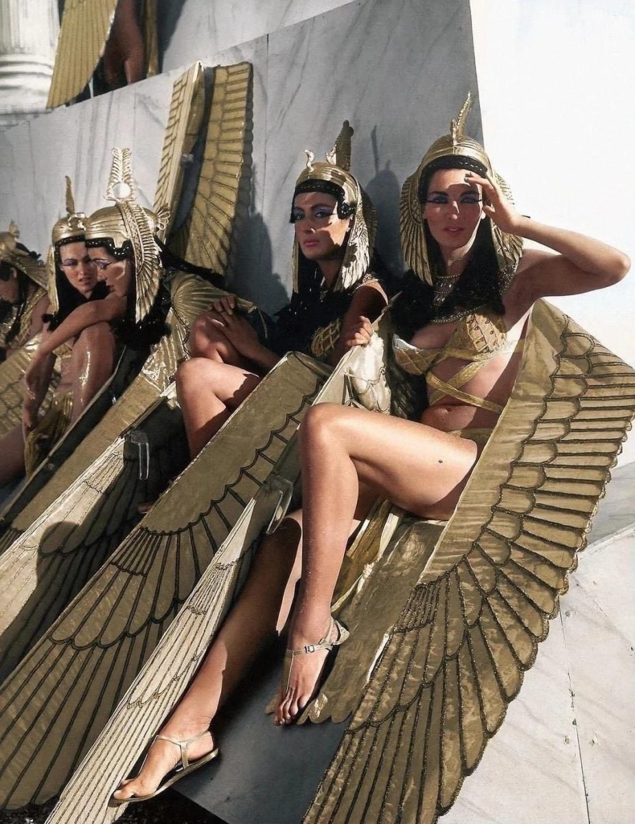 Ženy v egyptských kostýmoch s ohromujúcimi zlatými krídlami v dramatickom póze na čarovnom pódiu.