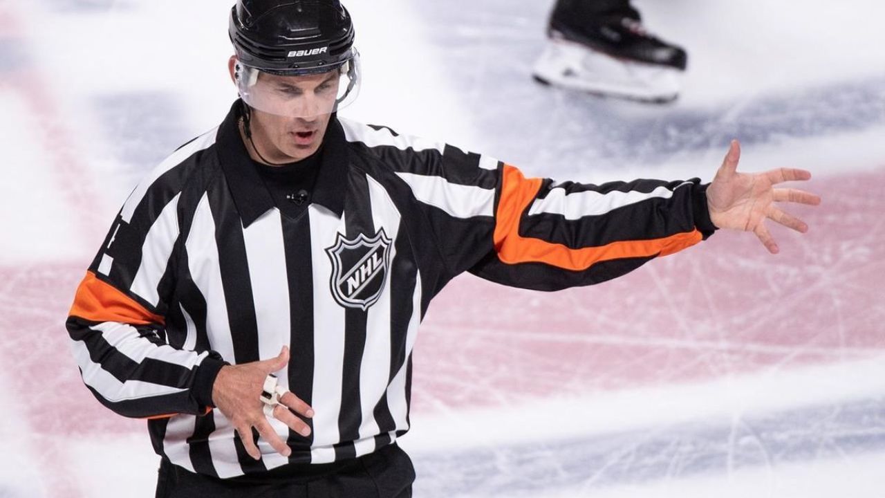 Hokejový rozhodca gesto predvádza na ľadovej ploche počas zápasu NHL.