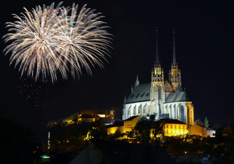 Ohňostroj nad osvetlenou katedrálou v Brne počas nočnej oblohy.