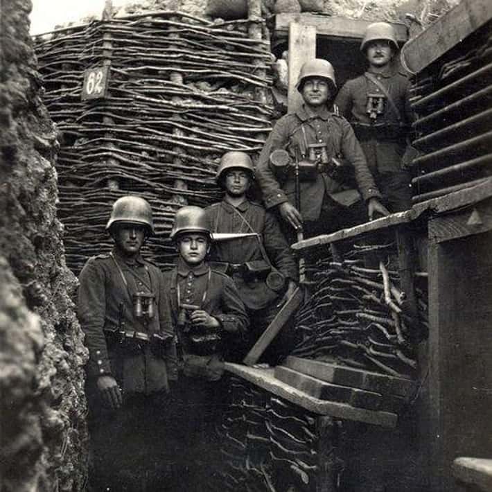 Vojaci v zákopoch počas prvej svetovej vojny, oblečení v uniformách a prilbách, s obrannými nástrojmi.