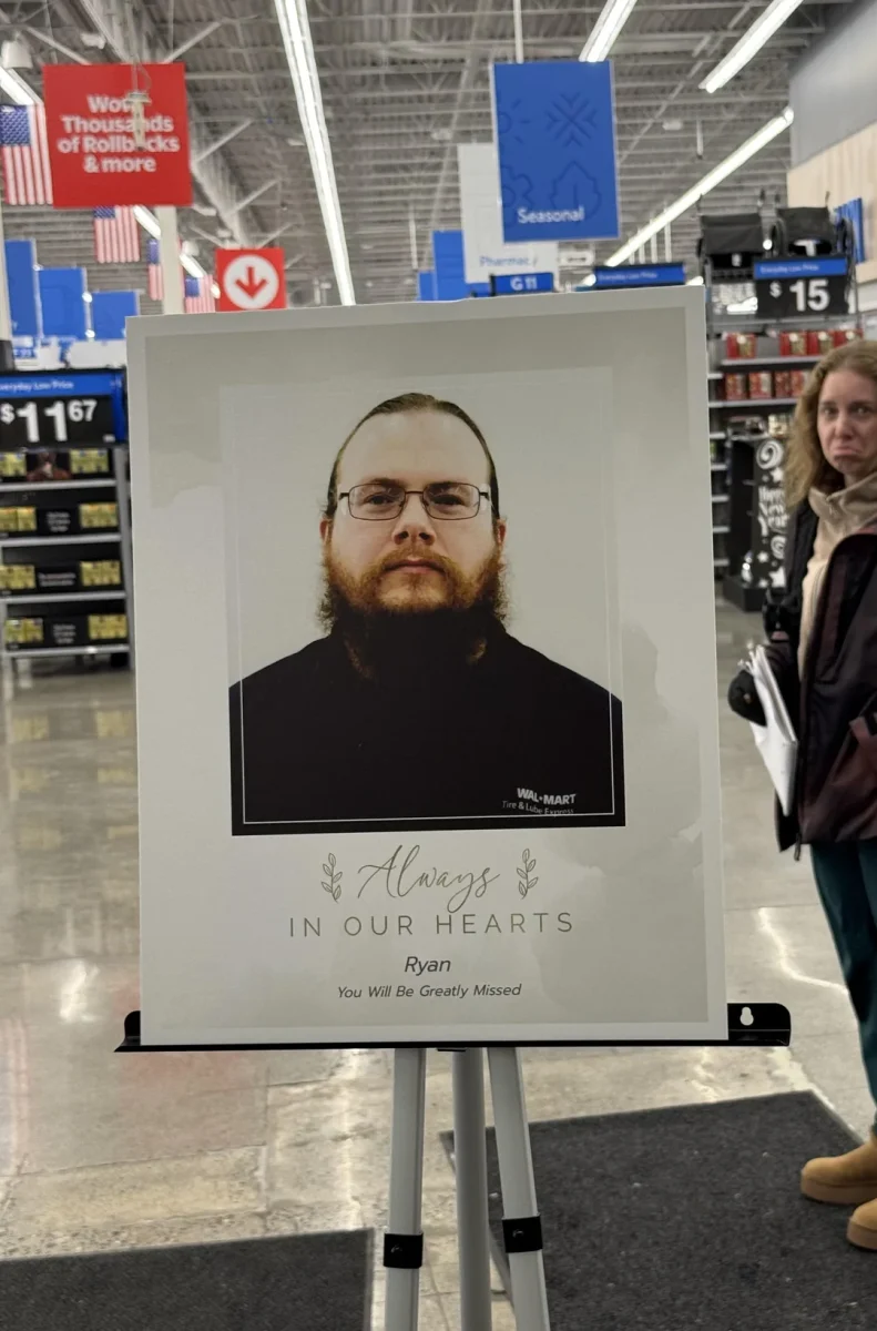 Obrázok pamätnej tabule so zamestnancom vo Wal-Mart predajni, Vždy v našich srdciach, zákazníci v pozadí.