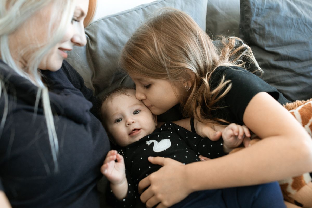 A cozy family moment with a mother and daughters bonding in a warm embrace.